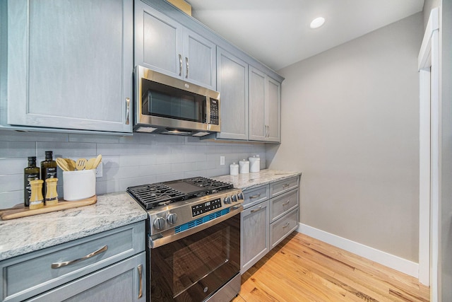 1115 Nature Trl, Manchester, MI 48158 - kitchen with light stone countertops, appliances with stainless steel finishes, light hardwood / wood-style flooring, and decorative backsplash