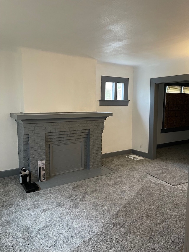 unfurnished living room with a brick fireplace and carpet floors