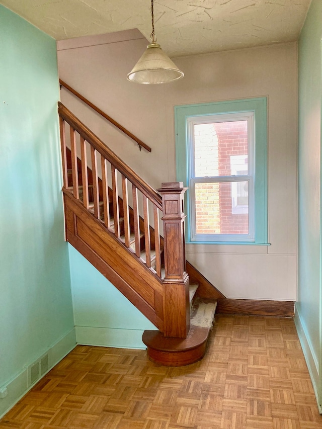 stairway featuring parquet floors