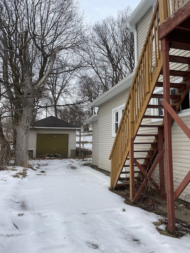 snow covered deck featuring a garage and an outbuilding