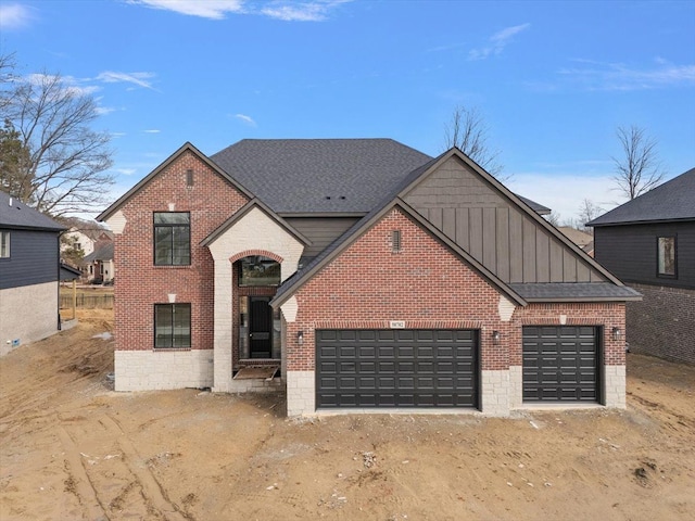 view of front of house with board and batten siding, roof with shingles, brick siding, and a garage