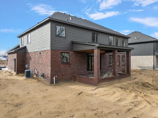 rear view of property with brick siding, a patio, and central AC