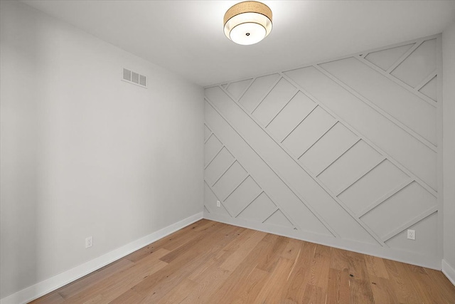 spare room with light wood-style floors, visible vents, and baseboards