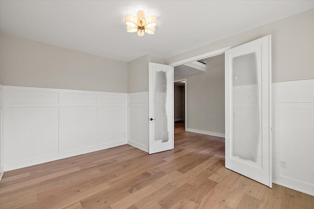 empty room featuring a notable chandelier and light wood-style floors