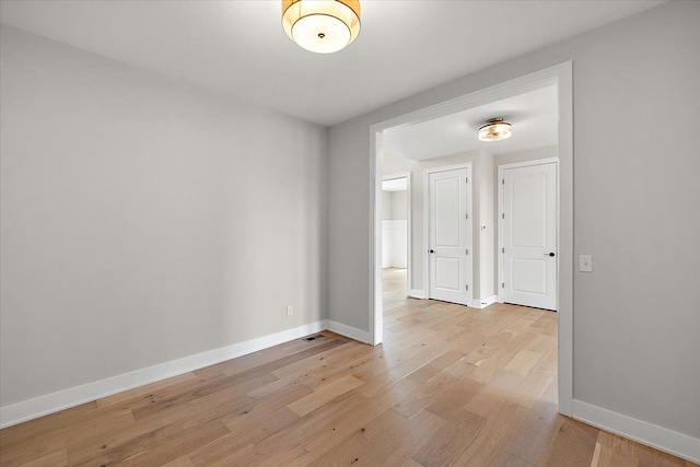 unfurnished room with light wood-type flooring and baseboards