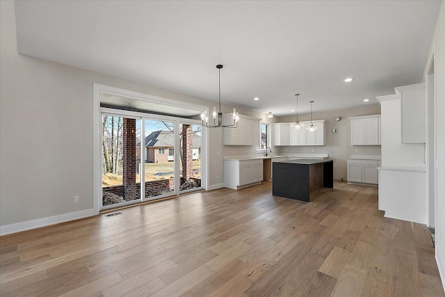 kitchen featuring light wood-type flooring, a kitchen island, visible vents, and white cabinets