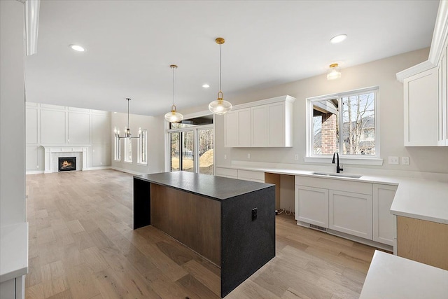 kitchen featuring plenty of natural light, a center island, light wood-type flooring, and a sink