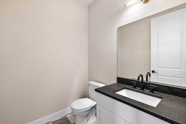 bathroom with toilet, baseboards, and vanity