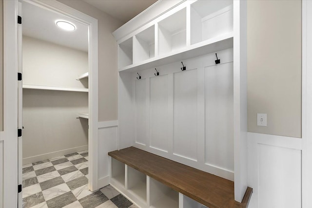 mudroom with light floors, wainscoting, and a decorative wall