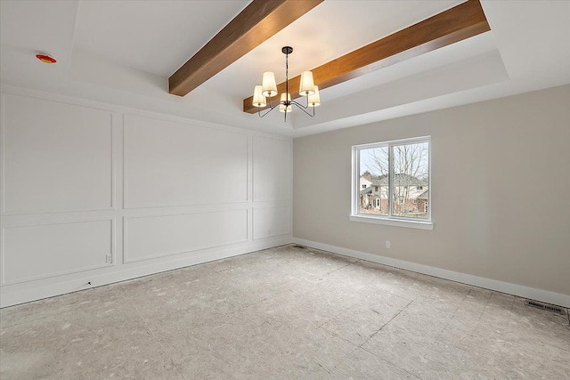 empty room with an inviting chandelier, a decorative wall, and a raised ceiling