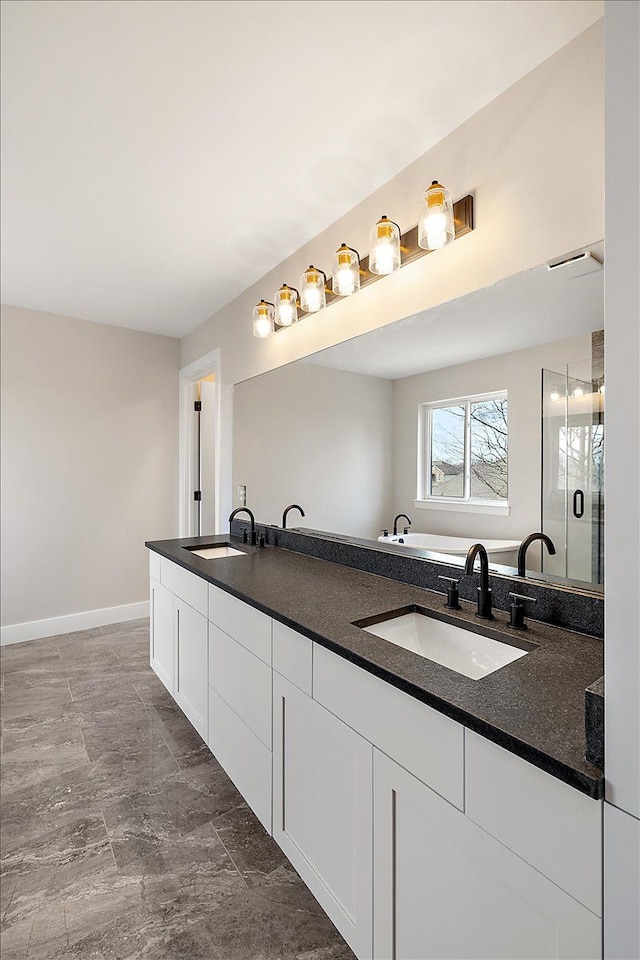 full bath with double vanity, a stall shower, a sink, and baseboards