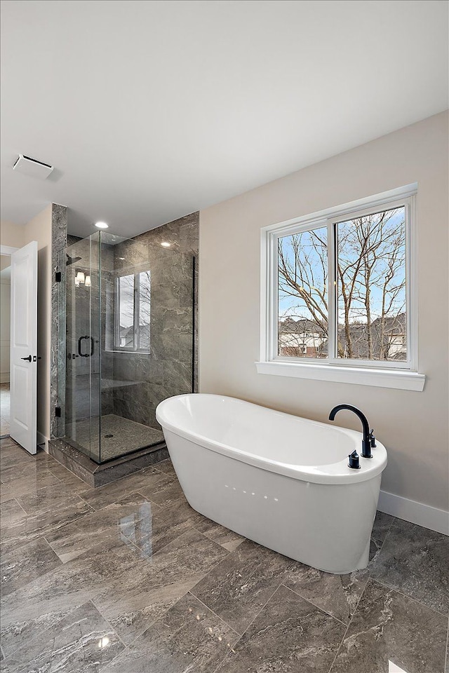 full bath featuring marble finish floor, visible vents, a shower stall, a freestanding tub, and baseboards