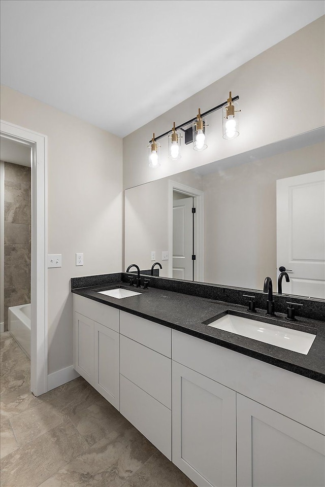 full bath with double vanity, a tub, baseboards, and a sink