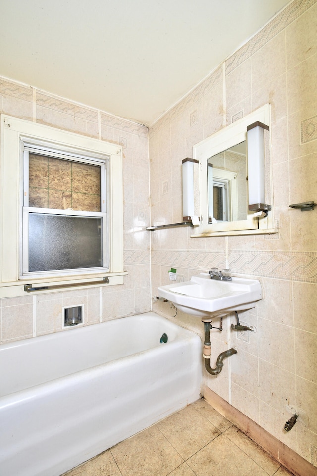 bathroom with tile patterned flooring, sink, tile walls, and a tub to relax in