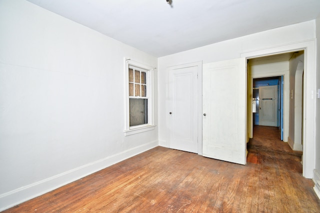 unfurnished bedroom featuring dark wood-type flooring and a closet