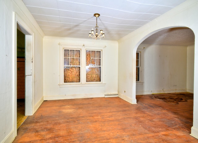 unfurnished dining area featuring crown molding, hardwood / wood-style floors, and an inviting chandelier