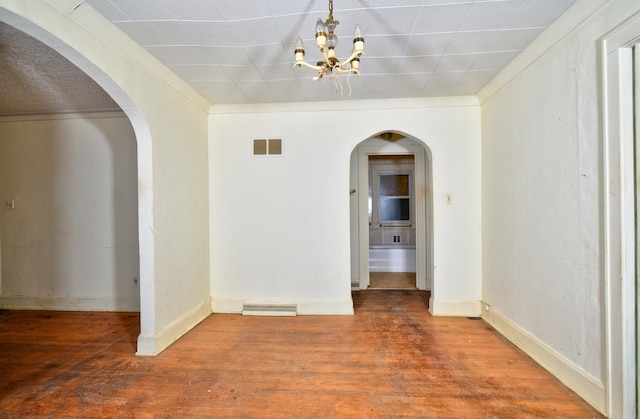 unfurnished room with hardwood / wood-style flooring and an inviting chandelier