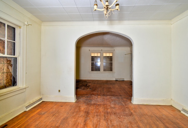 spare room featuring a notable chandelier, a baseboard radiator, and dark hardwood / wood-style floors