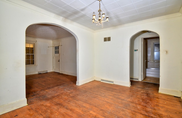 spare room featuring a notable chandelier, dark wood-type flooring, and ornamental molding