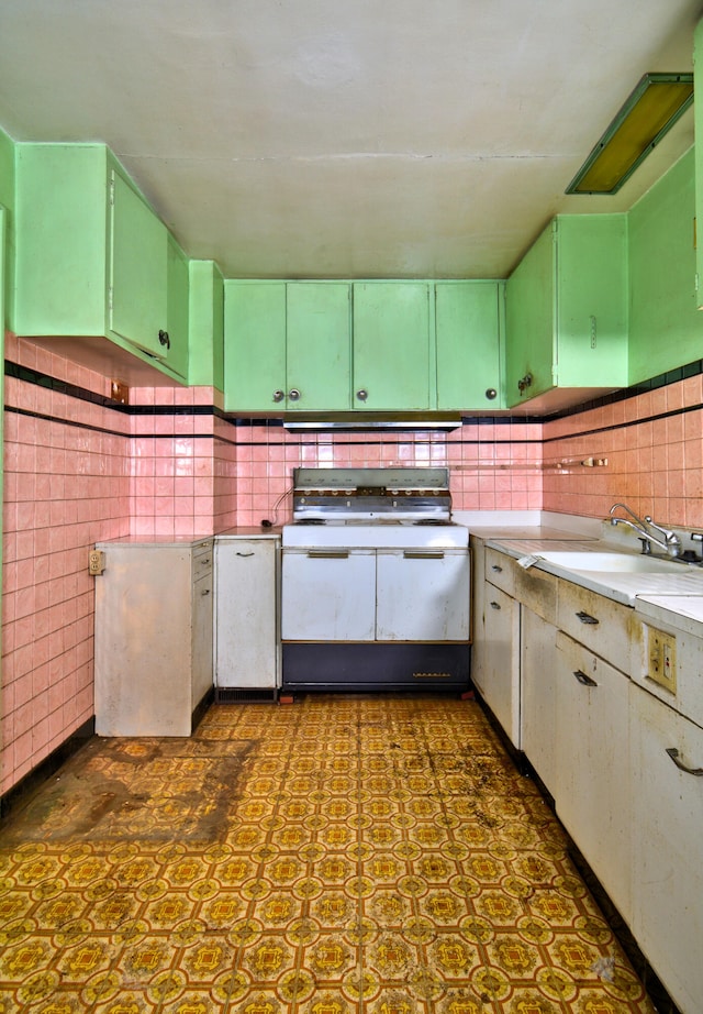 kitchen with green cabinetry, sink, tile walls, and white stove