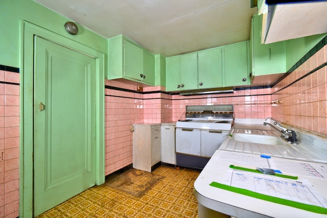 kitchen featuring white range oven, sink, tile walls, and green cabinetry