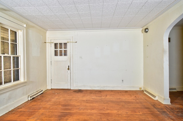 unfurnished room with wood-type flooring, crown molding, and baseboard heating