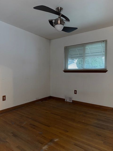 empty room featuring dark wood-type flooring and ceiling fan