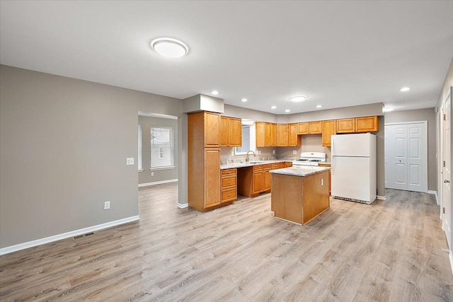 kitchen with light hardwood / wood-style floors, white appliances, a center island, and sink