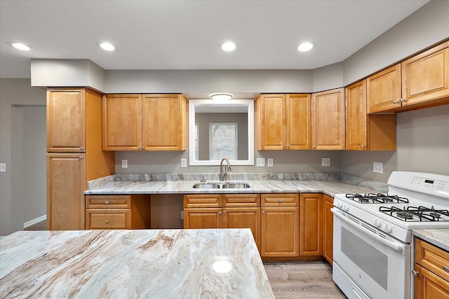 kitchen with light stone counters, sink, and gas range gas stove