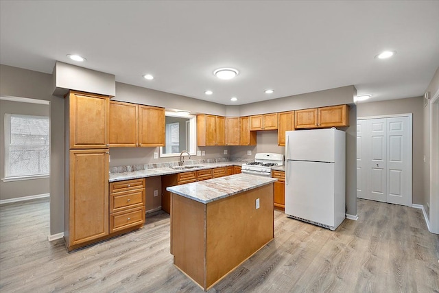 kitchen featuring sink, a center island, white appliances, light stone countertops, and light hardwood / wood-style floors