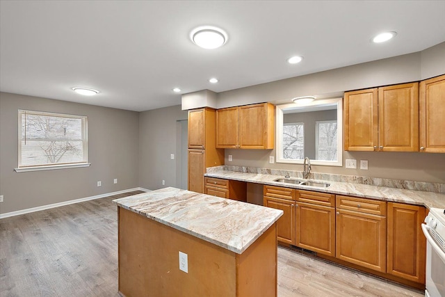 kitchen featuring a center island, sink, light stone countertops, and a wealth of natural light