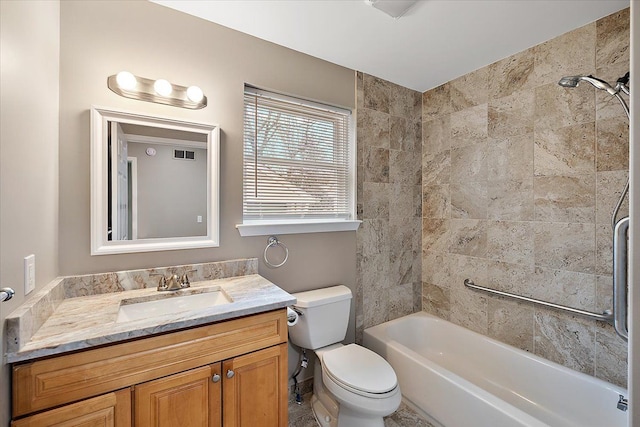 full bathroom featuring vanity, tiled shower / bath, and toilet