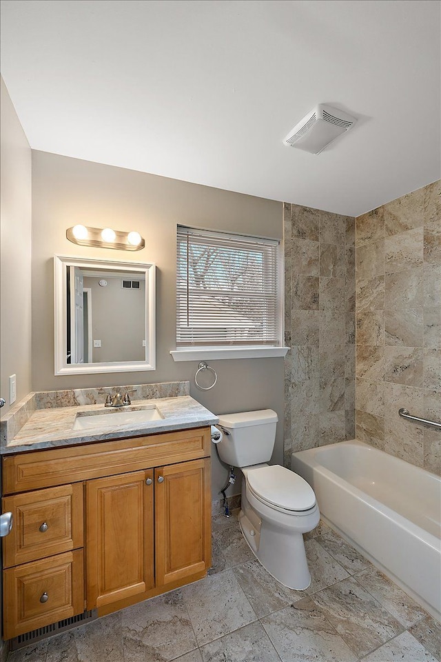 full bathroom featuring vanity, tiled shower / bath combo, and toilet