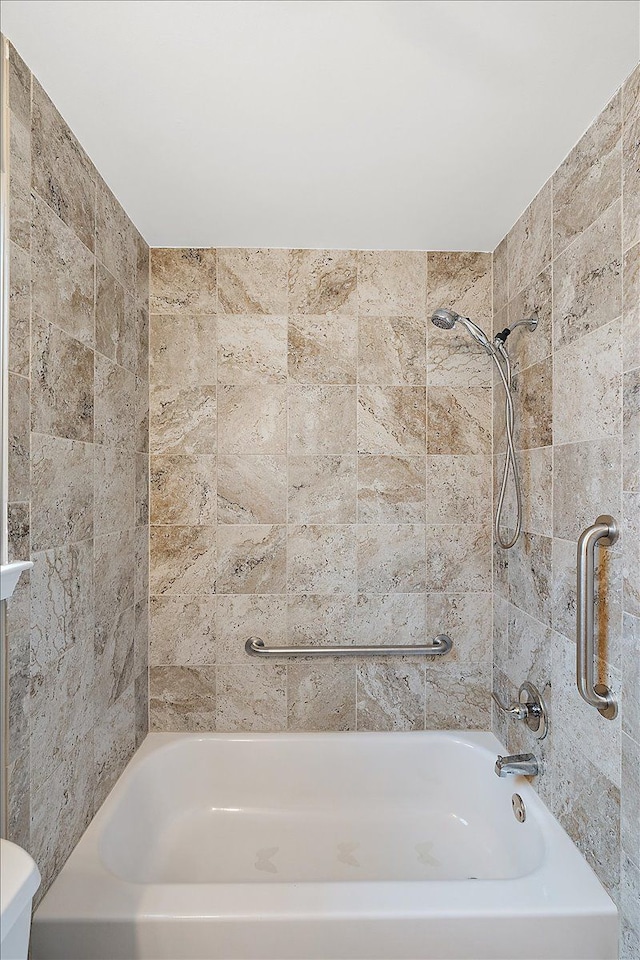 bathroom featuring tiled shower / bath and toilet