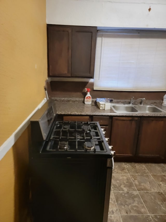 kitchen with stainless steel gas range, sink, and dark brown cabinets