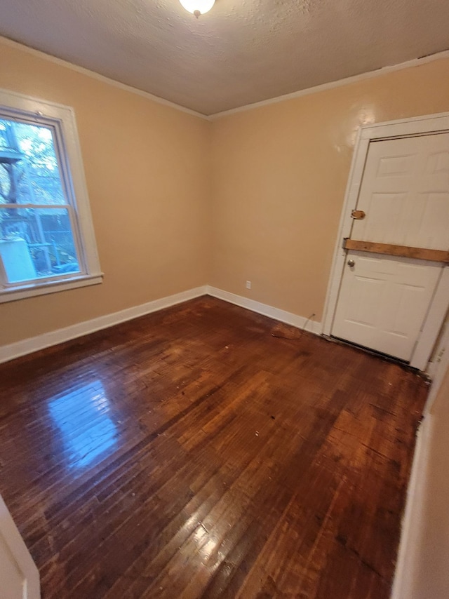 empty room featuring ornamental molding, dark hardwood / wood-style floors, and a textured ceiling