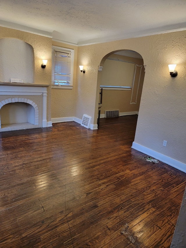 unfurnished living room featuring dark hardwood / wood-style flooring, a brick fireplace, and a textured ceiling