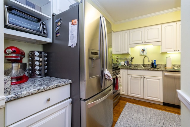 kitchen with stone counters, white cabinetry, sink, ornamental molding, and stainless steel appliances