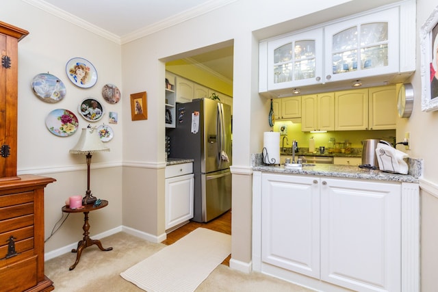 kitchen featuring stainless steel fridge, light stone countertops, ornamental molding, white cabinets, and light colored carpet