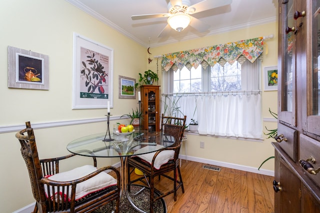 dining area featuring crown molding, wood-type flooring, and ceiling fan