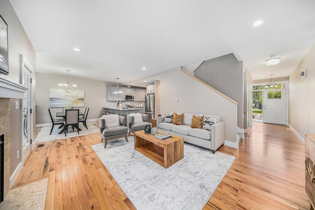 living room featuring sink, light hardwood / wood-style flooring, and a notable chandelier