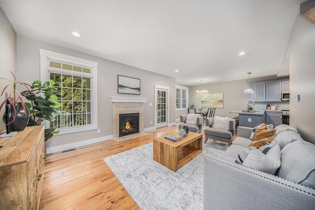 living room with an inviting chandelier, a fireplace, and light hardwood / wood-style floors