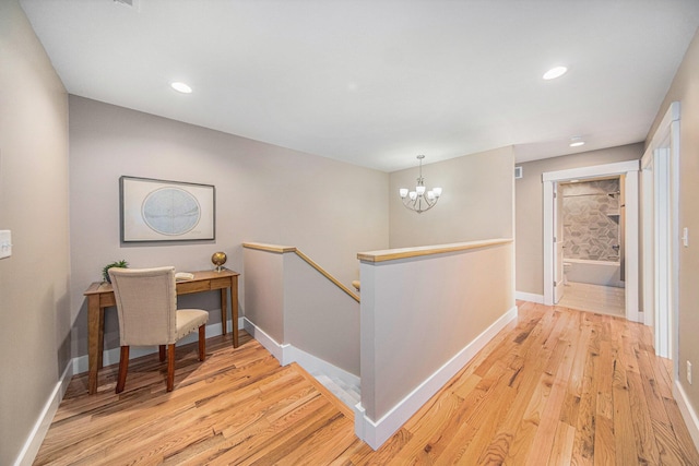 corridor with a chandelier and light hardwood / wood-style floors