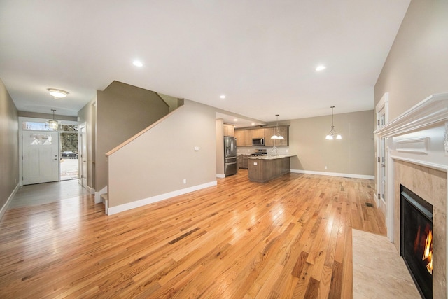 unfurnished living room featuring a tiled fireplace, sink, and light hardwood / wood-style floors