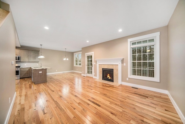 unfurnished living room featuring sink and light hardwood / wood-style floors