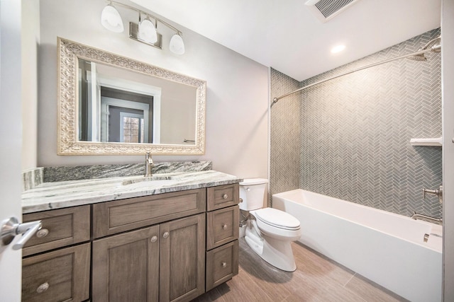 full bathroom with vanity, tiled shower / bath combo, wood-type flooring, and toilet