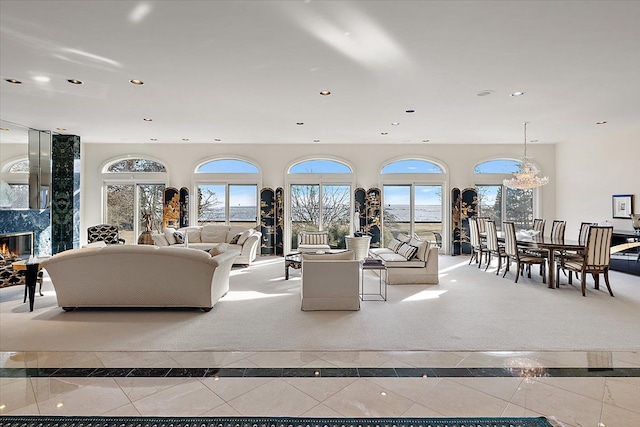 living room with light tile patterned floors, a chandelier, and a high end fireplace