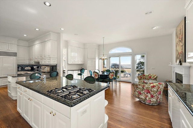 kitchen with pendant lighting, a center island, black gas cooktop, sink, and white cabinetry