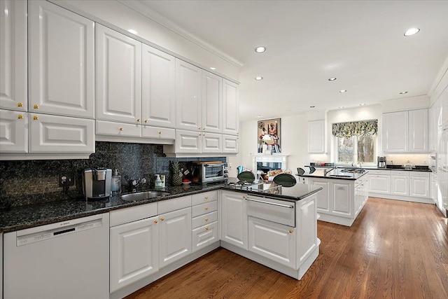 kitchen featuring dark stone countertops, white dishwasher, white cabinetry, and kitchen peninsula