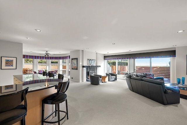 living room with ceiling fan, light colored carpet, and plenty of natural light